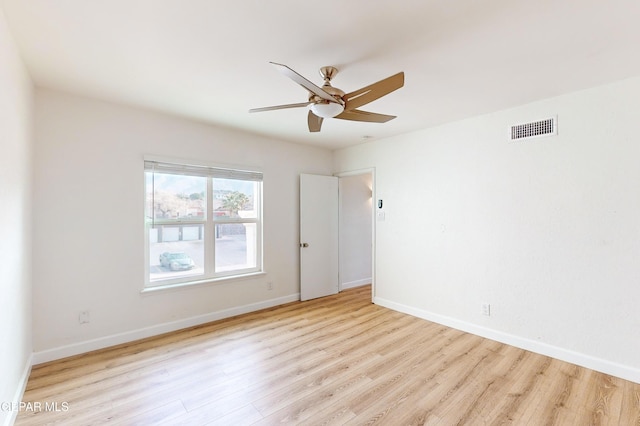 spare room featuring visible vents, a ceiling fan, baseboards, and wood finished floors