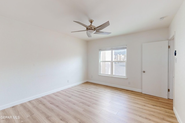 spare room with baseboards, light wood-style floors, and a ceiling fan