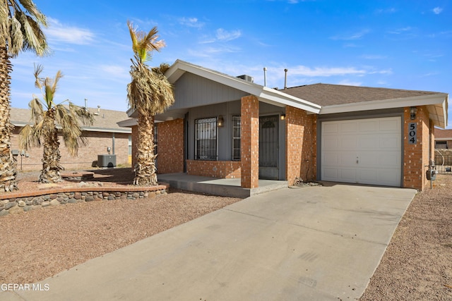 single story home featuring concrete driveway, brick siding, an attached garage, and a shingled roof