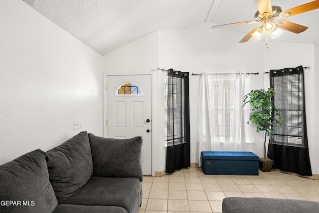 living area with a ceiling fan, lofted ceiling, a textured ceiling, and light tile patterned floors