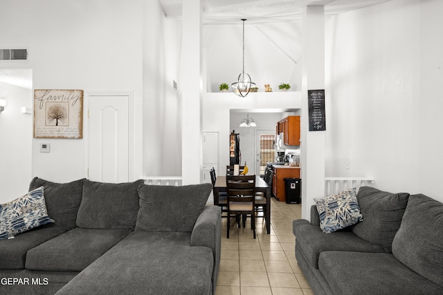 living area with light tile patterned floors, a high ceiling, visible vents, and an inviting chandelier