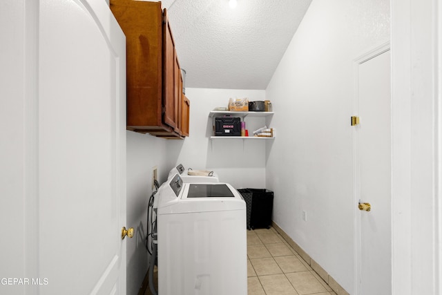 washroom with washing machine and clothes dryer, light tile patterned floors, cabinet space, a textured ceiling, and baseboards