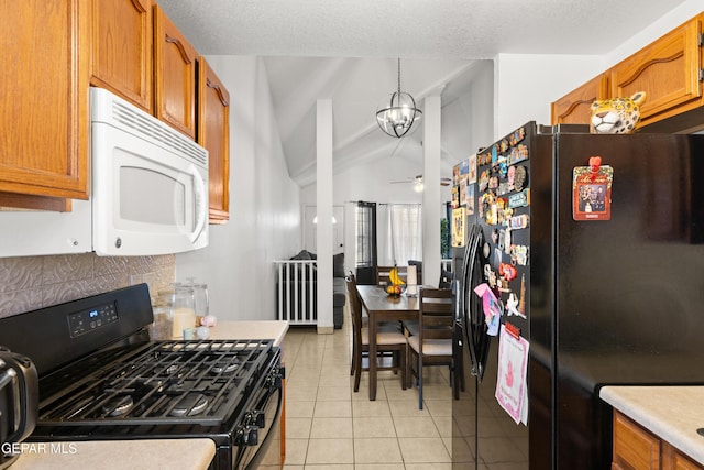 kitchen with light tile patterned floors, brown cabinetry, vaulted ceiling, black appliances, and ceiling fan with notable chandelier