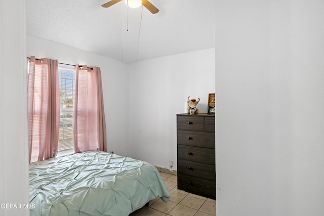 bedroom with vaulted ceiling, ceiling fan, a textured ceiling, and light tile patterned flooring