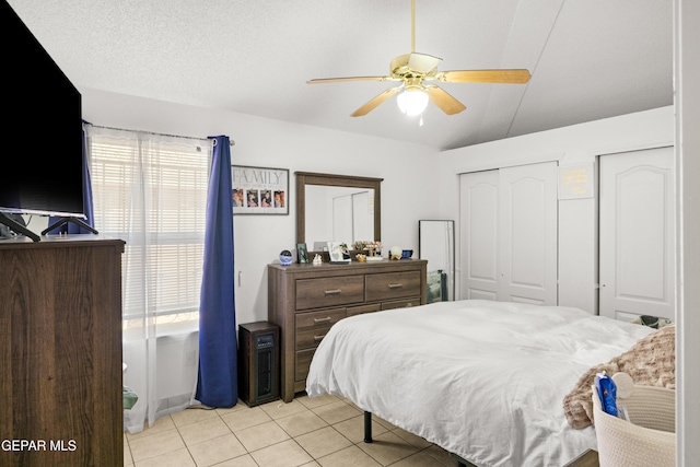 bedroom with multiple windows, vaulted ceiling, two closets, and light tile patterned flooring