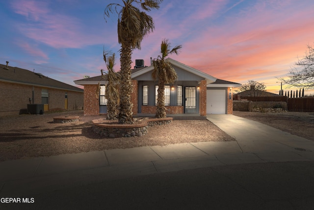 view of front of property with an attached garage, central air condition unit, driveway, and a fire pit