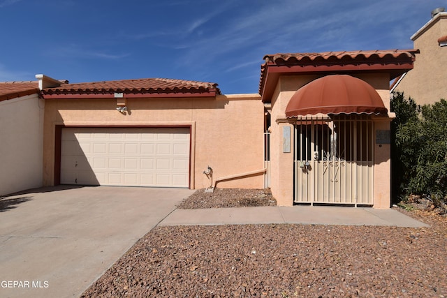 view of front facade with a garage, a tiled roof, concrete driveway, and stucco siding