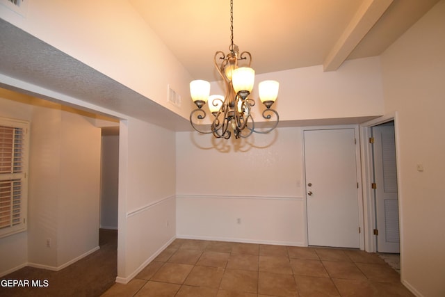 unfurnished dining area featuring visible vents, baseboards, tile patterned floors, beamed ceiling, and an inviting chandelier