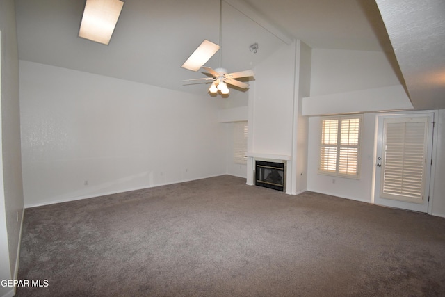 unfurnished living room with high vaulted ceiling, a glass covered fireplace, carpet flooring, and ceiling fan