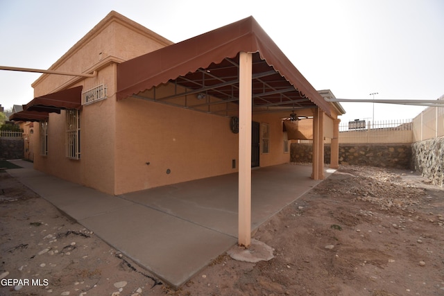 view of side of home featuring a carport, fence, a patio, and stucco siding