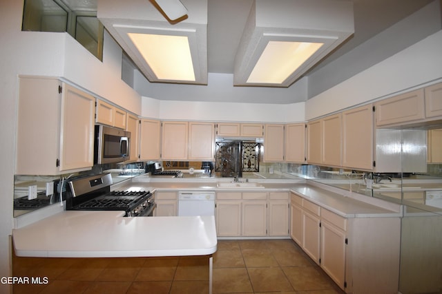 kitchen with stainless steel appliances, light countertops, a sink, and a peninsula