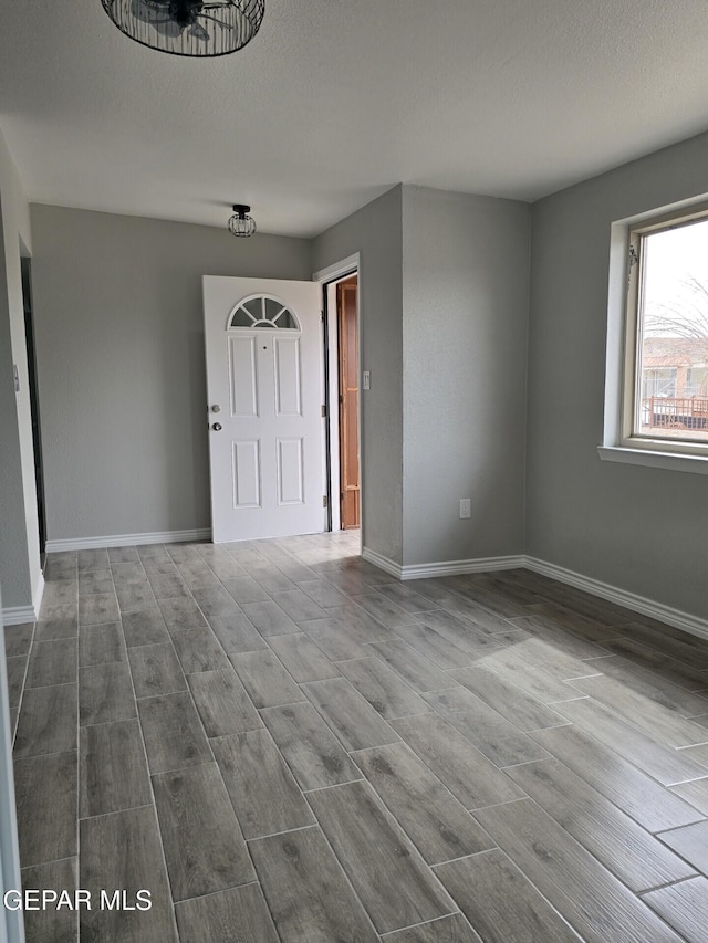 interior space featuring a textured ceiling, dark wood-type flooring, and baseboards