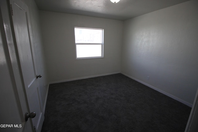 empty room with baseboards and dark colored carpet