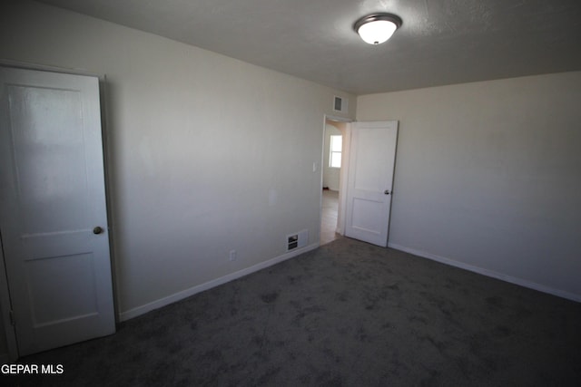 empty room featuring carpet flooring, visible vents, and baseboards