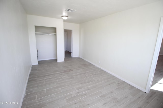 unfurnished bedroom with light wood-style floors, baseboards, visible vents, and a closet