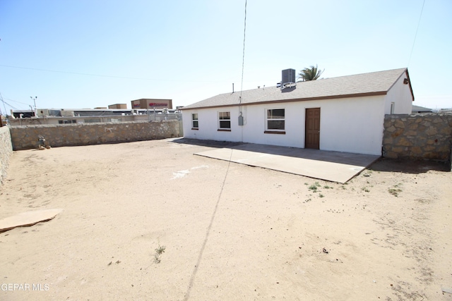 rear view of house with stucco siding, central AC, fence, and a patio