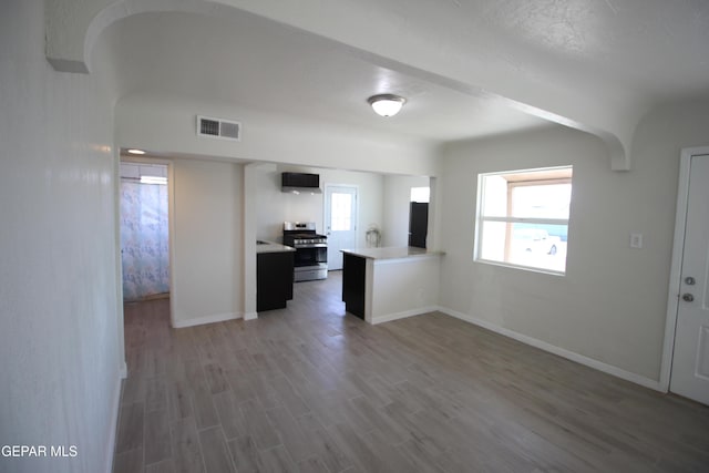 kitchen featuring wood finished floors, visible vents, baseboards, light countertops, and gas range