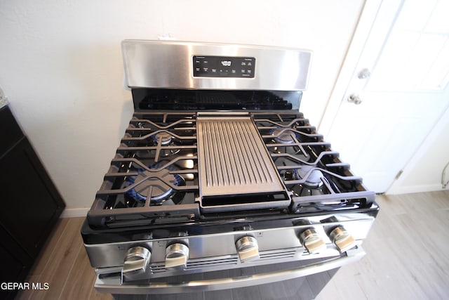 room details with baseboards, stainless steel range with gas stovetop, and wood finished floors