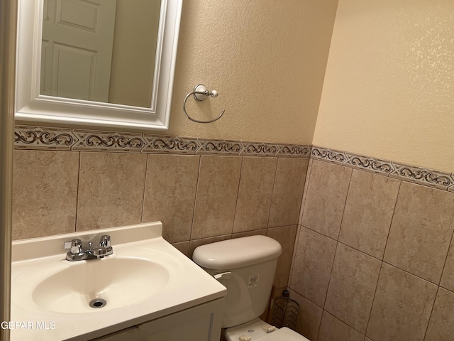 225 Peyton Rd, El Paso, TX 79928 - bathroom featuring tile walls, vanity, toilet, a textured wall, and wainscoting