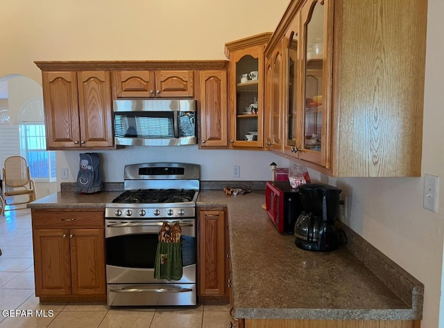 225 Peyton Rd, El Paso, TX 79928 - kitchen featuring appliances with stainless steel finishes, brown cabinets, dark countertops, and light tile patterned floors