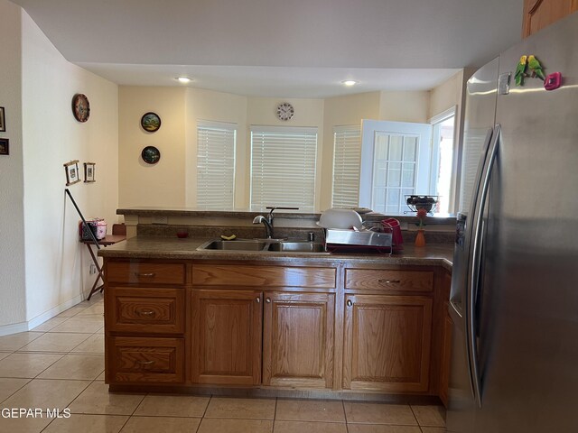 225 Peyton Rd, El Paso, TX 79928 - kitchen featuring stainless steel fridge, a sink, dark countertops, light tile patterned floors, and brown cabinetry