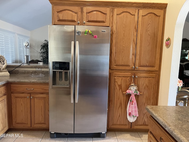 225 Peyton Rd, El Paso, TX 79928 - kitchen featuring stainless steel fridge with ice dispenser, light tile patterned floors, arched walkways, and brown cabinetry