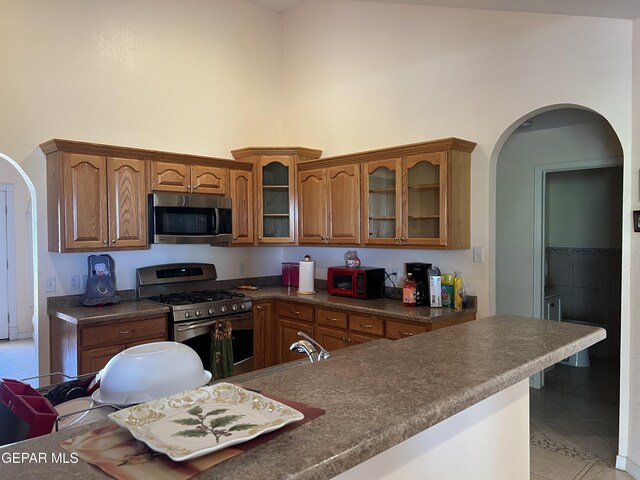 225 Peyton Rd, El Paso, TX 79928 - kitchen with stainless steel appliances, a high ceiling, light tile patterned floors, brown cabinetry, and dark countertops