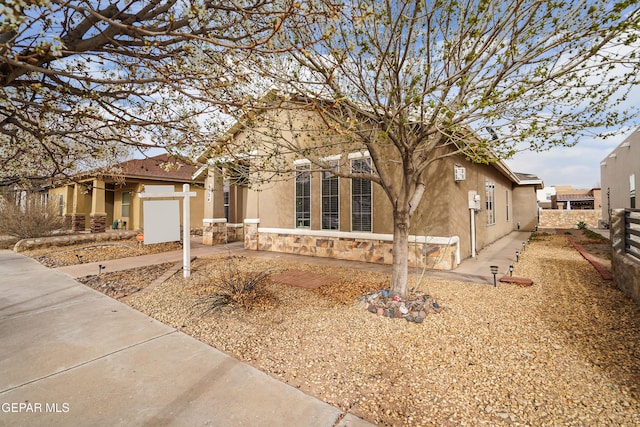 single story home featuring driveway, stone siding, fence, and stucco siding