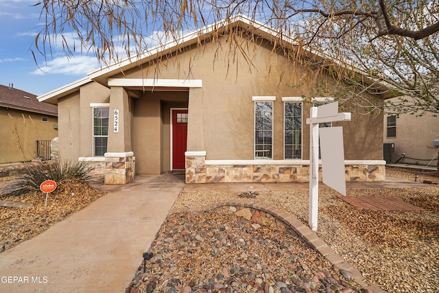 ranch-style home with stone siding, central AC unit, and stucco siding