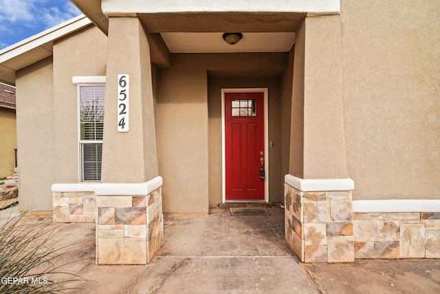 entrance to property featuring stone siding and stucco siding