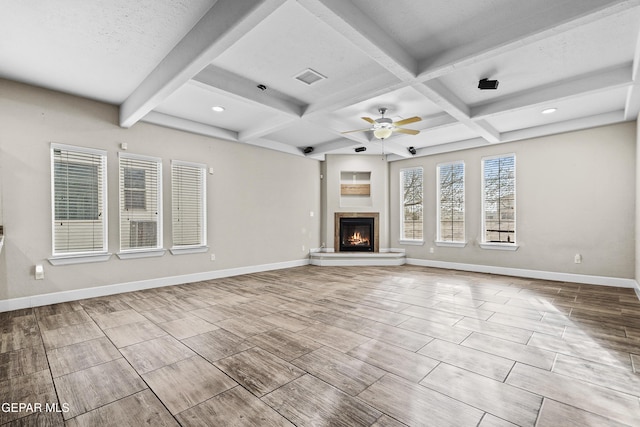 unfurnished living room with beam ceiling, visible vents, a ceiling fan, a lit fireplace, and baseboards