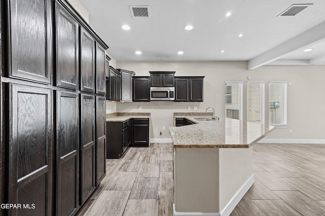 kitchen with baseboards, visible vents, stainless steel microwave, and a sink