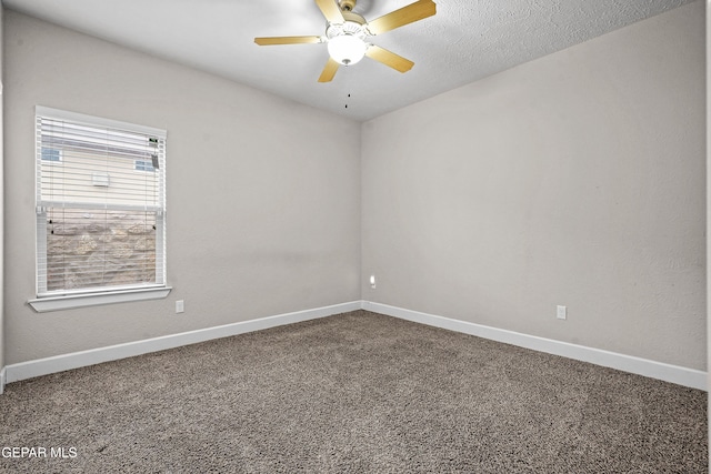 spare room with ceiling fan, dark colored carpet, a textured ceiling, and baseboards