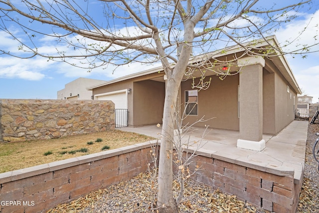 view of property exterior featuring a garage, fence, and stucco siding