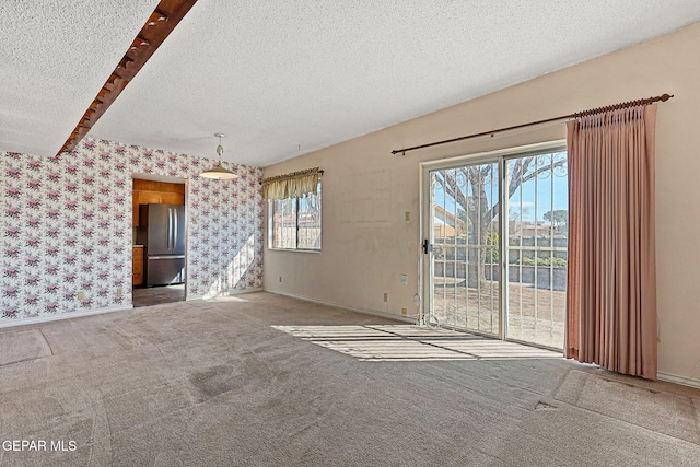 unfurnished living room featuring carpet flooring, a textured ceiling, wallpapered walls, and baseboards