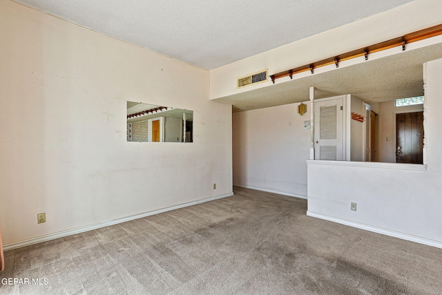 carpeted empty room featuring visible vents, a textured ceiling, and baseboards