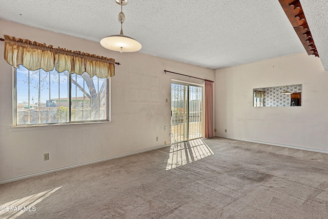 spare room featuring baseboards, carpet, and a textured ceiling