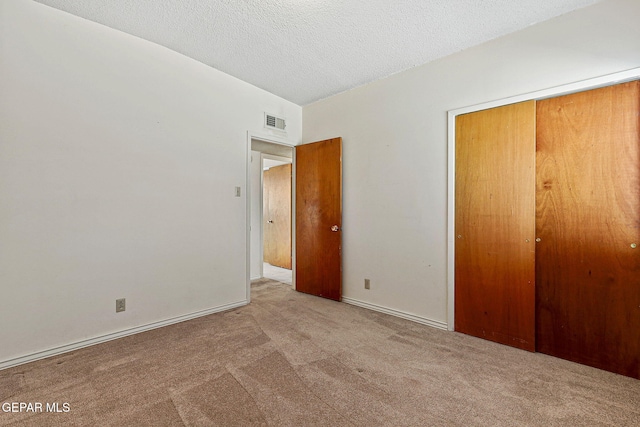 unfurnished bedroom featuring visible vents, baseboards, carpet floors, a closet, and a textured ceiling