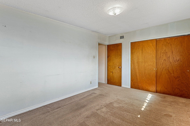 unfurnished bedroom featuring baseboards, visible vents, a closet, a textured ceiling, and carpet flooring