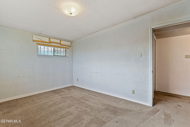 carpeted empty room with baseboards and a textured ceiling