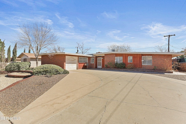 ranch-style home featuring concrete driveway, brick siding, and a garage