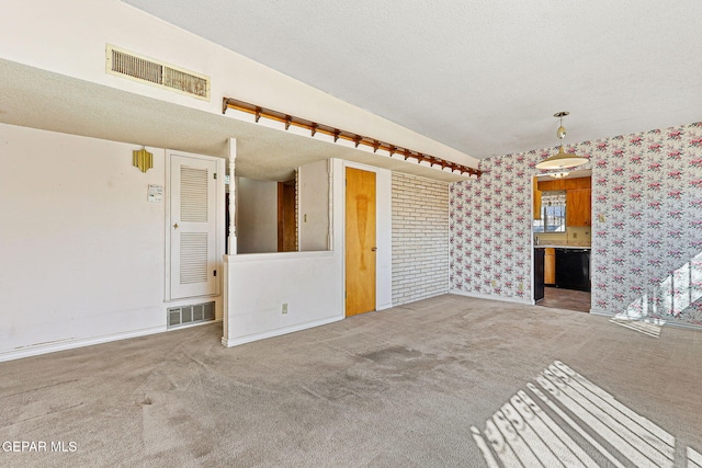 unfurnished living room featuring visible vents, carpet floors, a textured ceiling, and wallpapered walls