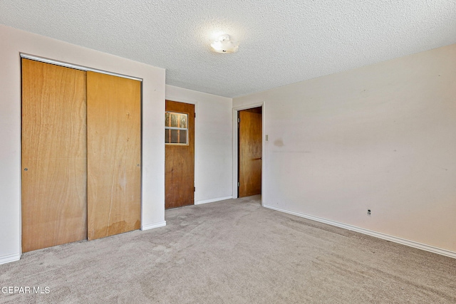 unfurnished bedroom with baseboards, carpet, a closet, and a textured ceiling