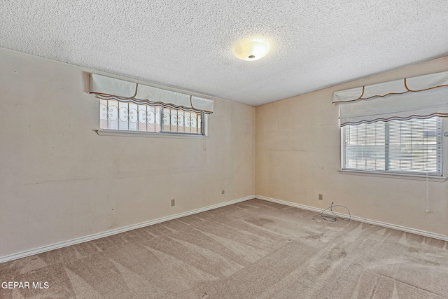 carpeted spare room with a textured ceiling and baseboards