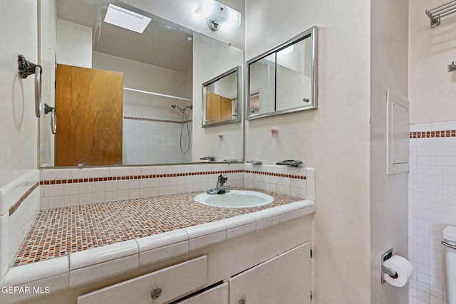 bathroom with walk in shower, toilet, tile walls, and vanity