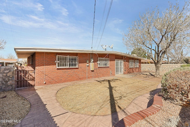 view of front facade featuring a patio area, fence, brick siding, and a gate