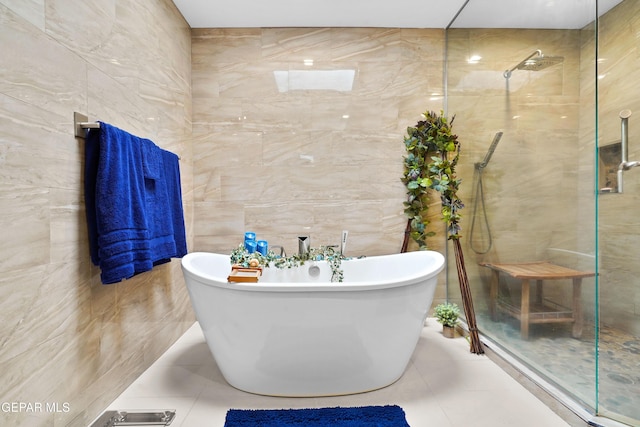 bathroom with tile patterned flooring, a freestanding bath, a tile shower, and tile walls