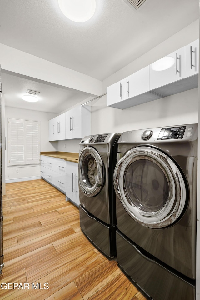 washroom featuring visible vents, light wood-style flooring, and washer and dryer