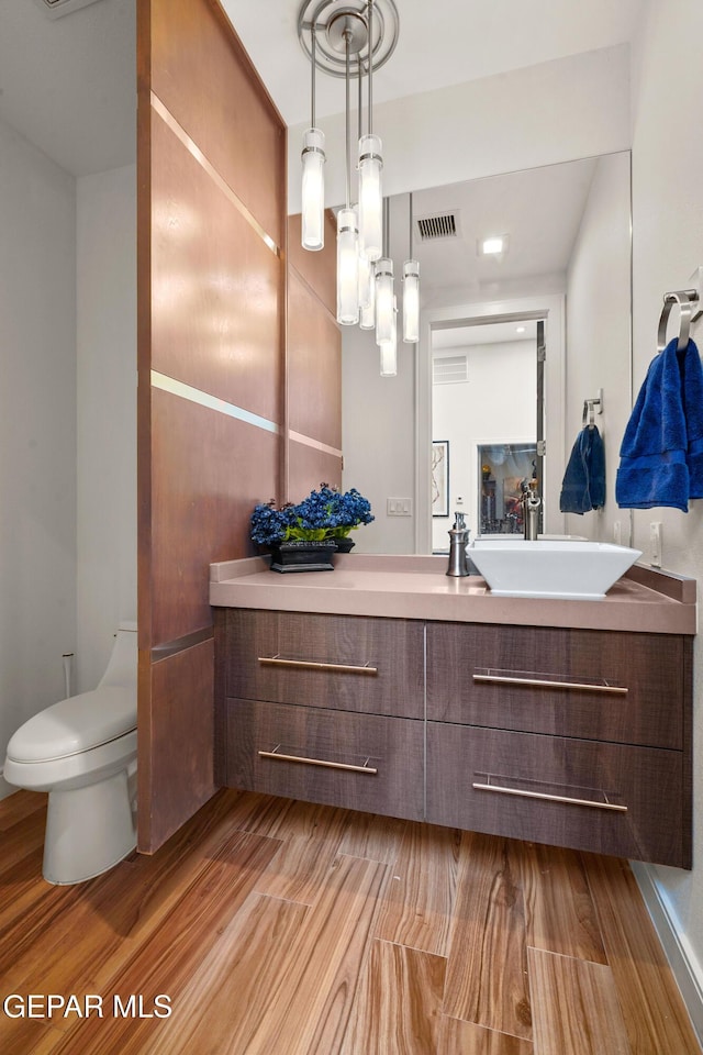 bathroom featuring toilet, wood finished floors, vanity, and visible vents