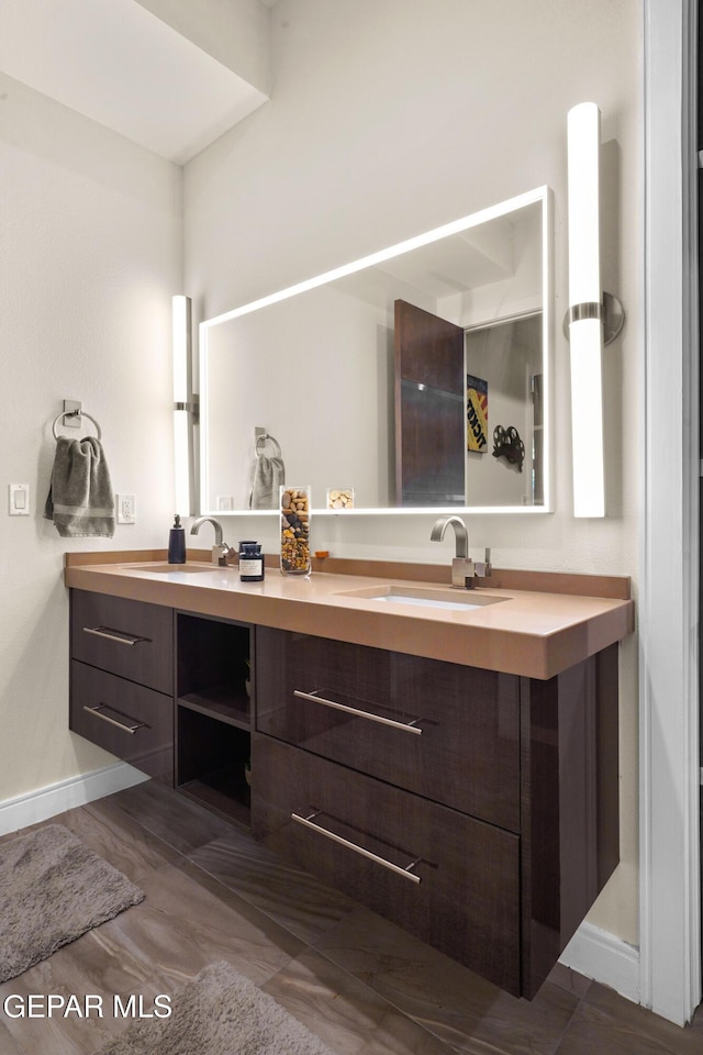 bathroom with a sink, baseboards, and double vanity